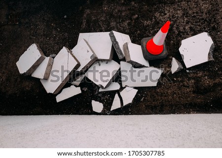 bright orange road cone and fragments of asphalt of white concrete when repairing the road from above
