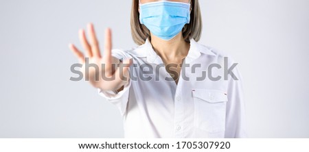 Studio portrait of Asian woman wearing face medical surgical mask hand showing a stop sign. Stop COVID-19 concept Mask protection against virus. Covid-19, coronavirus pandemic