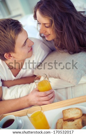 Vertical image of a smiling couple having breakfast in bed