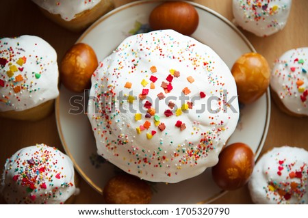 Homemade Easter cake for Easter with colored sprinkles, Easter picture, decorated craft eggs, natural painting of eggs with floral patterns. A lot of Easter cakes in a circle. On a wooden background.
