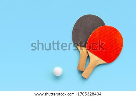 Red and black rackets for table tennis with white ball on blue background. Ping pong sports equipment in minimal style. Flat lay, top view, copy space Royalty-Free Stock Photo #1705328404