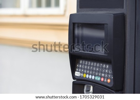 Modern automatic pay Parking meter or ticket payment station  on a street allow parkers, car drivers pay by card or cash cryptocurrency in the blurred background.
