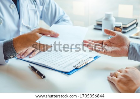 Doctor or physician writing diagnosis and giving a medical prescription to male Patient Royalty-Free Stock Photo #1705356844