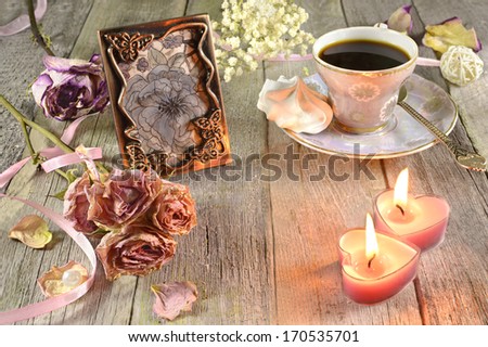 Vintage coffee cup with meringues, heart-shaped candles and bunch of flowers on wood