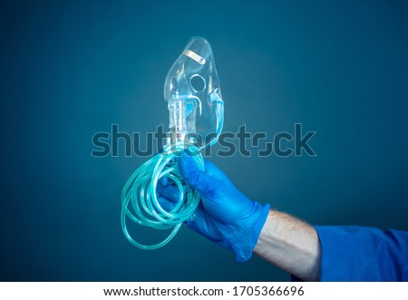 COVID-19 Outbreak. Exhausted Doctor holding non- invasive ventilator. Medical treatment and lack of equipment for coronavirus infected patients with SARS. Shortage of medical ventilators in hospitals. Royalty-Free Stock Photo #1705366696