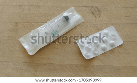 tablets and syringe on a wooden background