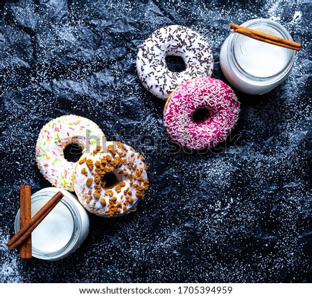 Top view of breakfast with donuts and milk, with cinnamon sticks on a black background