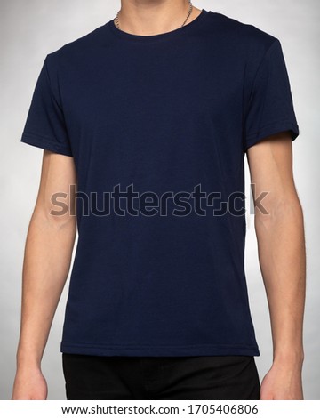 guy in a dark blue plain t-shirt clothes stands with his hands down on a light gray background