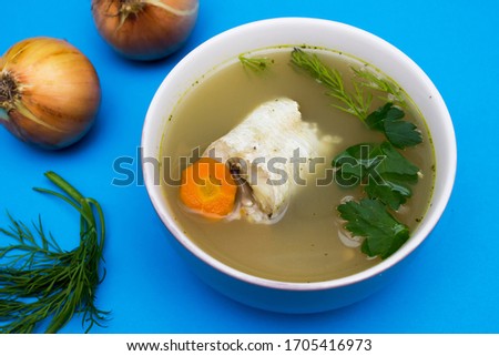 Traditional fish soup. Blue background. Fish soup is a food made by combining fish or seafood with vegetables and stock