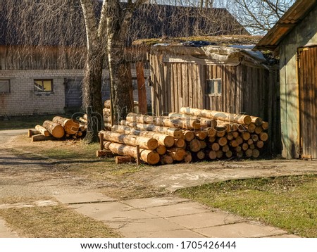 picture with a farm barn and prepared firewood for the winter, a simple household yard