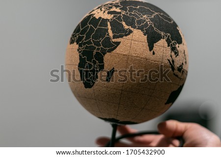 Still life, office design, global map on cork sphere. Eco friendly, sustainable materials. New green deal economy, environmnetal matters. South of the world in one hand. Royalty-Free Stock Photo #1705432900