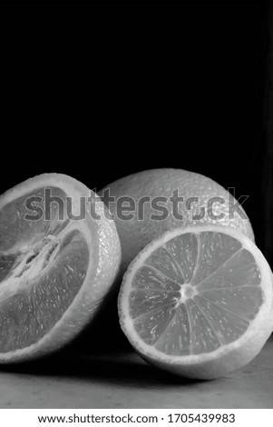Black and white picture, orange lemon. On a black background.