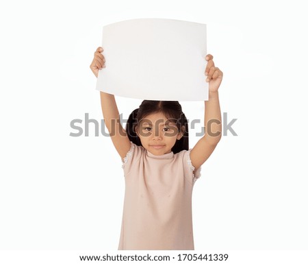 A little girl holds a blank A4 paper sheet above a head and free space for text isolated on white background.