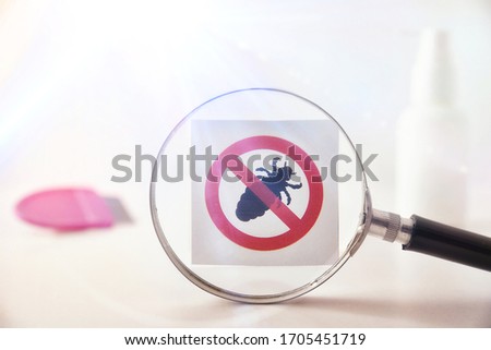 Lice prevention concept with magnifying glass focusing on drawing of prohibited lice and accessories in the background. Horizontal composition. Front view
