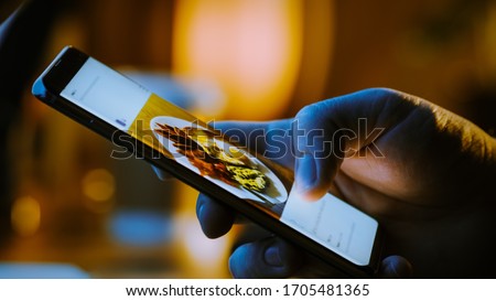 Close-up Macro: Person Holding and Using Smartphone, Browsing through Pictures on Social Network Wall. Finger Scrolling Social Media App Feed: Travel, Animals, Food. Mock-up Application Design Royalty-Free Stock Photo #1705481365