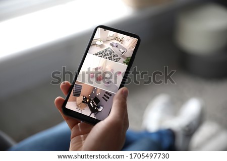 Man monitoring modern cctv cameras on smartphone indoors, closeup. Home security system Royalty-Free Stock Photo #1705497730