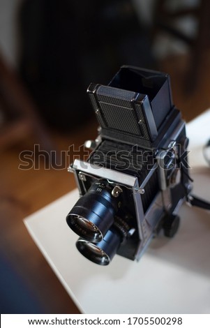 A medium format film camera sitting on a desk with soft focus