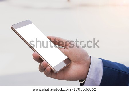 Closeup business man holding smartphone with white screen in the modern city. Business and finance concept.