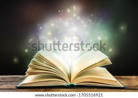 Magic light emanating from open old book on table Royalty-Free Stock Photo #1705516921