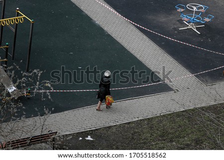 Covid 2019 Quarantine time. Woman with shopping bag crosses closed playground while quarantine time in Moscow, spring 2020. World crisis. Stay home concept. 