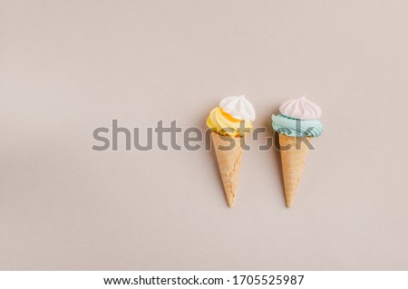 Small crispy waffle ice cream cups with colored marshmallows on a pastel background