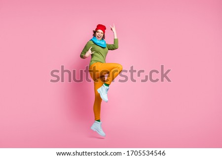 Full size photo energetic girl jump enjoy rejoice spring sales rock and roll concert make horned symbol scream wear red blue yellow green shoes pants headwear isolated pink color background
