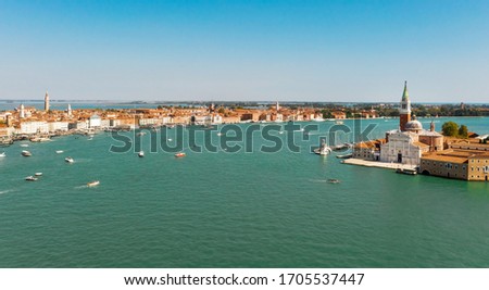 Aerial panoramic shot of Venice city and Grand Canal, Italy. View from above. Tiled roofs and nerros streets. Venetian atmosphere. Blue sky and lagoon water. Historical buildings.