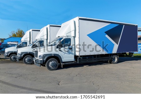 Three new white trucks ready for departure are parked. Delivery or shipment of goods in a conceptual manner.