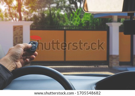 Man in car, hand using remote controller to open the automatic garage. Home remote control and security system  concept. 