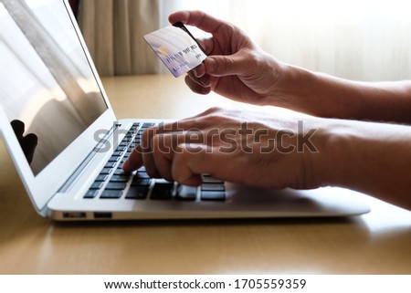 Men hand holding credit card and type payment information on keyboard for order online shopping. Internet technology and Digital market place E-Commerce lifestyle concept, Social distance during Covid