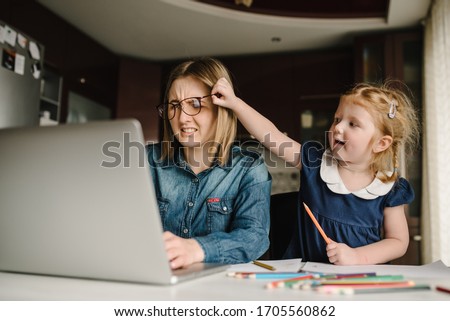 Mother working from home with kid. Quarantine and closed nursery school during coronavirus outbreak. Child make noise and disturb woman at work. Homeschooling and freelance job. Stay at home. Royalty-Free Stock Photo #1705560862