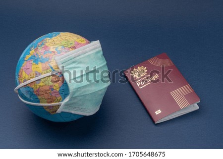 Medical mask put on globe globe with portuguese european passport on blue background.