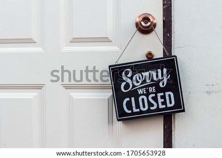 Sorry we're closed sign. grunge image hanging on a white door.