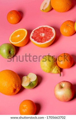 grapefruit, orange, apple, pear lie on a pink background
