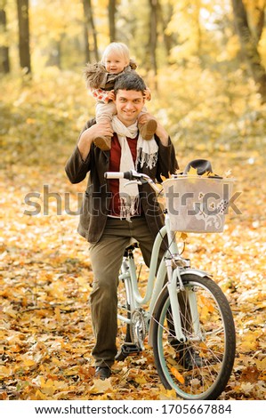 Father and little daughter have fun on the same bike. Autumn photo shoot.