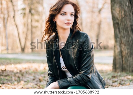 spring photo portrait of a girl in a leather jacket and pants in the park