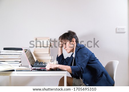 Young woman with dark blue jacket and shorts remotely teaching play  chess through online education at home. Quarantine. Coronavirus situation. Employee. Teacher. Background.