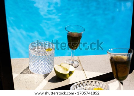 two glasses and an apple next to the pool with the mirror effect