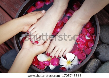 Closeup photo of a female feet at spa salon on pedicure procedure. Female legs in water decoration the flowers with film grain effect