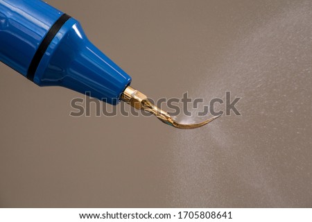Dental ultrasonic scaler with water splash. Periodontal ultrasonic scaler is a dental instrument used primarily in the prophylactic and periodontal care of human teeth - tartar removal. Royalty-Free Stock Photo #1705808641