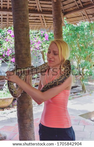 Woman with scary face holding snake in Vietnam village. Picture is noisy and main subject has motion blur