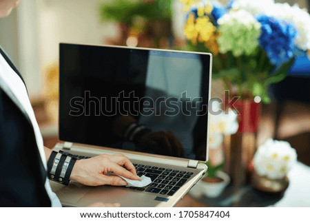 Closeup on housewife cleaning laptop keyboard with cleaning cloth in the house in sunny day.
