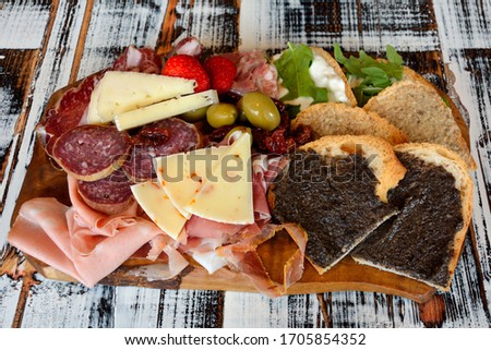 Big Italian cutting board with crostini, sausage, ham, olives and strawberries in San Marino Royalty-Free Stock Photo #1705854352