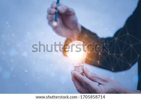 Businessman Catch the light bulb on blue background dark polygon digital network with using line flying globe social interaction concept.