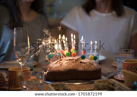 Birthday Party with the Family! Layed Table with heartshaped Cake and Many lighted Candles. Realistic Image