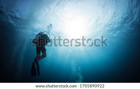 Silhouette scuba diver swim in the deep blue ocean