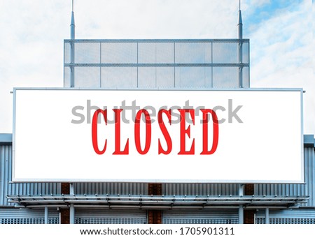 Billboard with sign CLOSED on shop against a cloudy blue sky