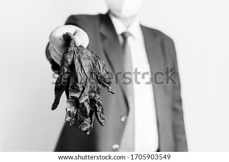 Young man businessman in a white protective mask holds out his hand in which he holds black gloves. Prevention of viral diseases. Hygiene rules.