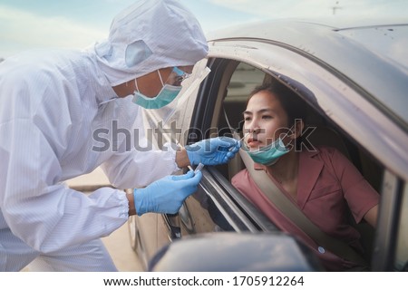 Medical worker in protective suit screening woman Driver to Sampling secretion to check for Covid-19. Drive thru test coronavirus fast track. Concept prevention coronavirus outbreak. Royalty-Free Stock Photo #1705912264