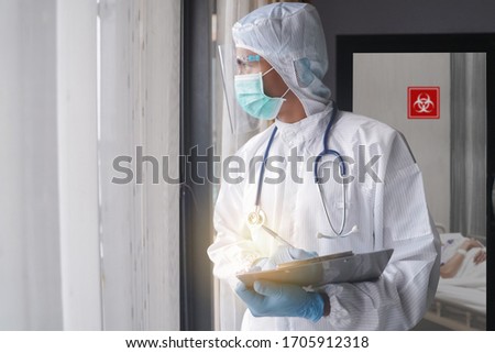 Medical worker or Doctors in the protective suits and masks in COVID 19 restricted area and looking for Coronavirus infected patient's laboratory report.